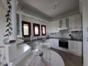 a kitchen with white cabinets and a table in it at Villa Paradies in Káto Lekhónia