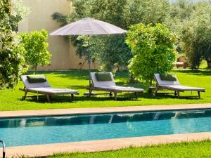 two chairs and an umbrella next to a pool at Villa A Atlas Retreat Luxury B and B Beni Mellal in Beni Mellal