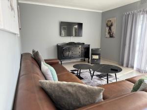 a living room with a brown couch and a table at Riverhaven Cottage in Muldersdrift