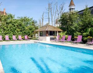 a swimming pool with pink chairs and a gazebo at Auberge du Bon Laboureur Chenonceaux in Chenonceaux