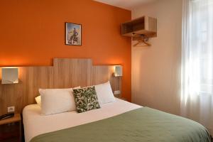 a bedroom with a bed with an orange wall at Logis Hôtel Restaurant Maison Voltaire in Amboise