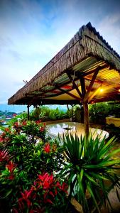 a patio with a straw umbrella and some plants at The Cliff Villa in Kubupenlokan +20 photos
