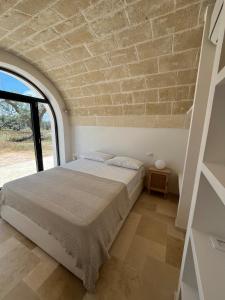 a bedroom with a bed and a brick wall at Trullo La Rosmarina in San Michele Salentino
