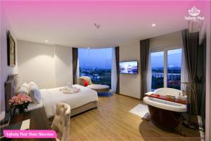 a hotel room with a bed and a sink and a tub at Infinity Pink Hotel Riverview in Danang