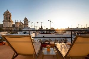 Un balcón con dos sillas y una mesa y un edificio. en Apartamento Las 3 Terrazas, en Cádiz