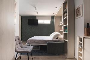 Un pequeño dormitorio con una cama y una silla. en Apartamento Las 3 Terrazas, en Cádiz