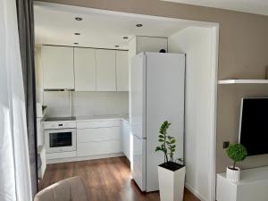 a kitchen with white cabinets and a refrigerator at SORD apartment in Liepāja