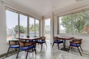 a dining room with two tables and chairs and windows at Soni's Mansion-100m from Khajuraho Temples in Khajurāho