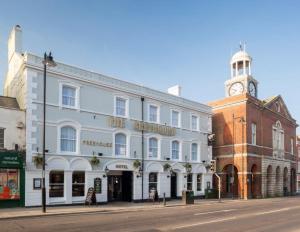 een groot wit gebouw met een klokkentoren op een straat bij The Greyhound Wetherspoon in Bridport