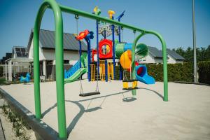 a playground with a swing set in front of a building at Domki Morski Raj B in Dębki