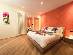 a bedroom with a large bed with an orange wall at Essenze di Bosco - Alpine Stay Apartments in Predazzo