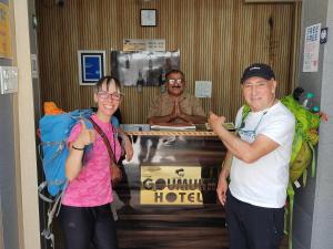乌德尔格希Gomukh Hotel Uttarkashi的一男一女站在摆着雕像的桌子旁