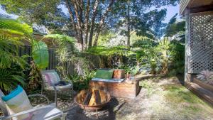 een achtertuin met een vuurplaats en een stoel bij The Treehouse -Pet Friendly, Heated Spa in Pearl Beach