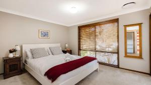 een slaapkamer met een groot bed en een raam bij The Treehouse -Pet Friendly, Heated Spa in Pearl Beach