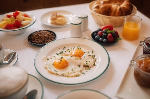a table with a plate of eggs and fruit at Romantik Spa Hotel Elixhauser Wirt in Elixhausen