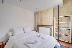 a bedroom with a large white bed and a fireplace at Cozy duplex - Heart of Chartrons in Bordeaux