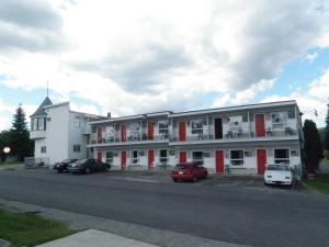 a large white building with cars parked in a parking lot at Almo Court Motel in Cranbrook