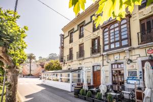 a building with tables and umbrellas on a street at Apartamento Ría San Esteban in San Esteban de Pravia