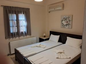 a bedroom with a bed with white sheets and a window at Dodis Village in Platanias