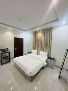 a bedroom with a white bed and a window at شقق درة الغيم للشقق المخدومة in Taif