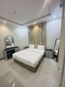 a bedroom with a large white bed and a mirror at شقق درة الغيم للشقق المخدومة in Taif +8 photos