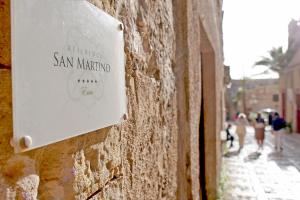 un cartel en una pared con gente caminando por una calle en Residence San Martino, en Erice