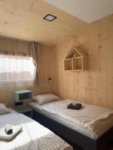 two beds in a room with wooden walls at Camp Ante-Gojko in Grebaštica