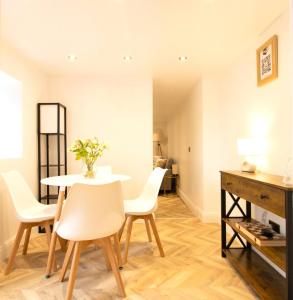 a dining room with a white table and chairs at Bubbles Bliss - Hot Tub Garden Pass the Keys in Rye
