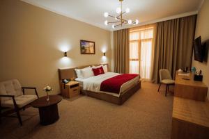 a hotel room with a bed and a chair at Mardan Hotel in Shymkent