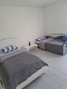 a bedroom with two beds and a table in it at Garden- pool apartman in Petrovice Donje