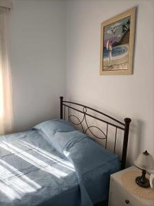 a bed with a blue blanket and a picture on the wall at Casa Giulia West Samos Lekka Hills Karlovasi 3BR Village Home in Samos