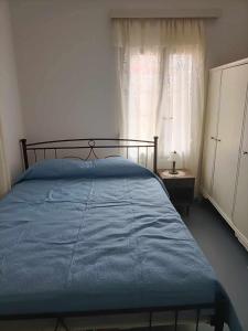 a bedroom with a bed with a blue comforter and a window at Casa Giulia West Samos Lekka Hills Karlovasi 3BR Village Home in Samos