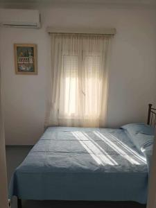 a bed in a room with a window with a blue blanket at Casa Giulia West Samos Lekka Hills Karlovasi 3BR Village Home in Samos
