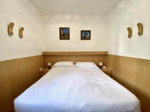 Cozy flat in amazing central location في كورتينا دامبيتزو: غرفة نوم بها سرير كبير مع وسادتين