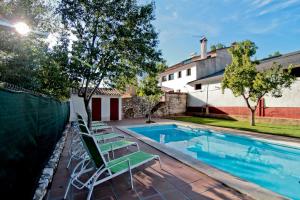 a swimming pool with lounge chairs next to a house at LA SERRERÍA in Galaroza