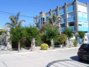 a street in front of a building with trees at Los Aromos Apart Spa in Las Grutas