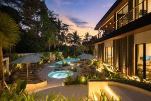an outdoor swimming pool with umbrellas and a resort at Villa Baliga Ubud by BaliSuperHost in Ubud