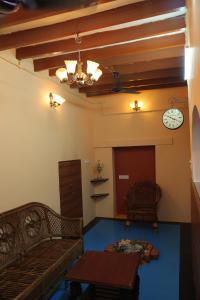 a living room with a couch and a clock on the wall at Tharavaadu by Le Apex in Puducherry