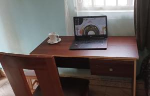 a laptop computer sitting on top of a wooden desk at Private room wz full DStv Package, Patio & Kitchenette in Kampala