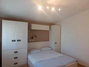 a bedroom with a bed and a white cabinet at APARTMAN I SOBE MARIJANA in Rab