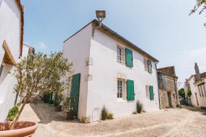 ein weißes Gebäude mit grünen Rollläden auf einer Straße in der Unterkunft La Do Ré - Élégante et chaleureuse maison à La Noue in Sainte-Marie-de-Ré