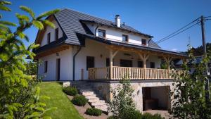 a white house with a porch and a balcony at CHALUPA U ROUBÍČKŮ in Horní Bečva