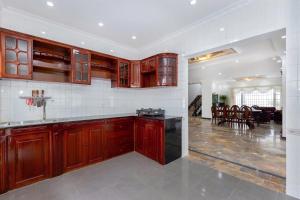 a kitchen with wooden cabinets and a dining room at Villa Luxury Hồ Bơi Bãi Sau Vũng Tàu in Vung Tau