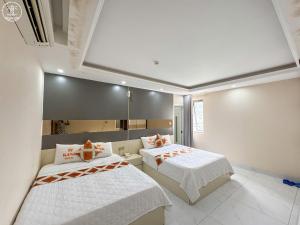 a bedroom with two beds with white sheets and orange pillows at KING Hotel in Vung Tau