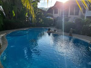 a boy sitting in a swimming pool with a fountain at Amy Village Apartments & Digital Hub in Lamai