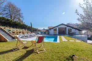 kilka krzeseł siedzących w trawie przy basenie w obiekcie Villa Olaina - Villa climatisée avec piscine w mieście Saint-Jean-de-Luz