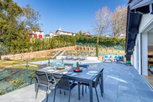 patio ze stołem i krzesłami na tarasie w obiekcie Villa Olaina - Villa climatisée avec piscine w mieście Saint-Jean-de-Luz