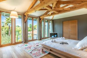 a bedroom with a large bed and large windows at Villa Julia - Villa contemporaine avec piscine in Anglet
