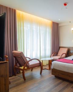 a hotel room with a bed and chairs and a window at Senora Suites in Kannur +30 photos