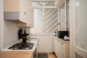 Una cocina blanca con estufa y ventana. en Dimora Borgo Pineta, en Castellaneta Marina
